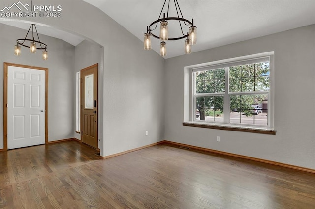 foyer entrance with arched walkways, a notable chandelier, lofted ceiling, wood finished floors, and baseboards