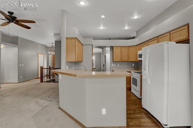 kitchen featuring recessed lighting, a peninsula, white appliances, light countertops, and light brown cabinetry