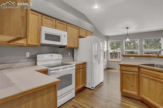 kitchen featuring white appliances, lofted ceiling, light countertops, pendant lighting, and a sink