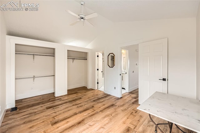 unfurnished bedroom featuring baseboards, a ceiling fan, lofted ceiling, wood finished floors, and multiple closets