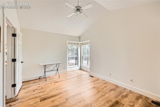 spare room featuring baseboards, visible vents, vaulted ceiling, a textured ceiling, and light wood-type flooring