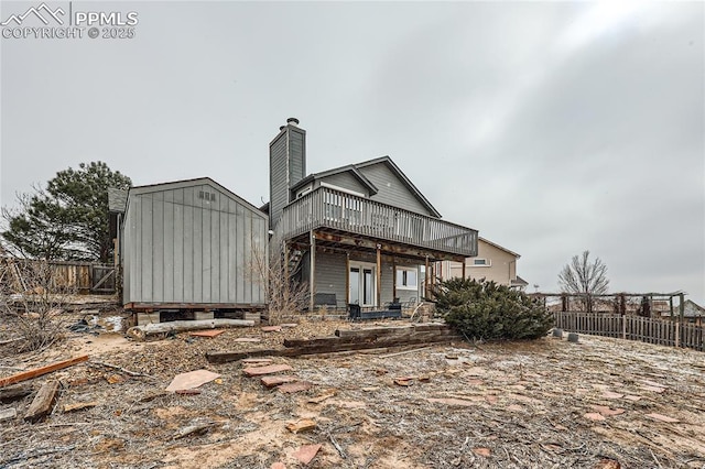 back of property featuring a chimney, fence, and a deck