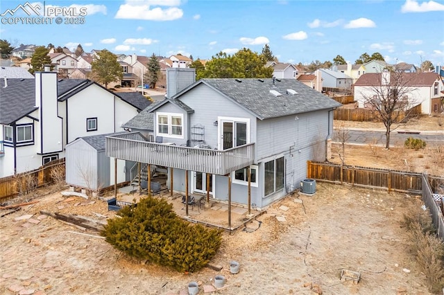 back of property featuring a fenced backyard, central AC, a shingled roof, a residential view, and a patio area