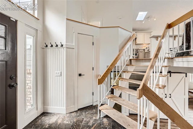 entryway featuring a wealth of natural light, marble finish floor, stairway, and a high ceiling