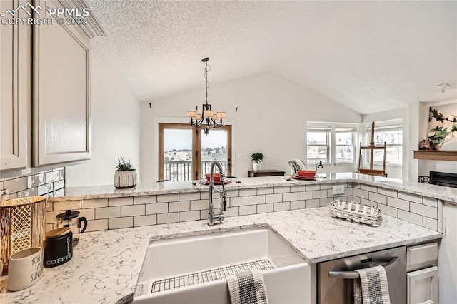 kitchen featuring light stone counters, vaulted ceiling, a sink, and decorative light fixtures