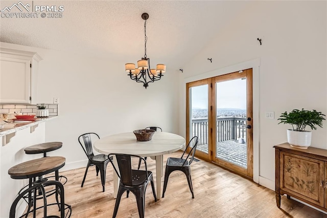 dining space with lofted ceiling, an inviting chandelier, light wood-style floors, a textured ceiling, and baseboards