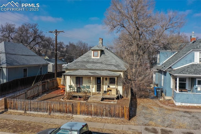 back of house featuring covered porch and a fenced front yard