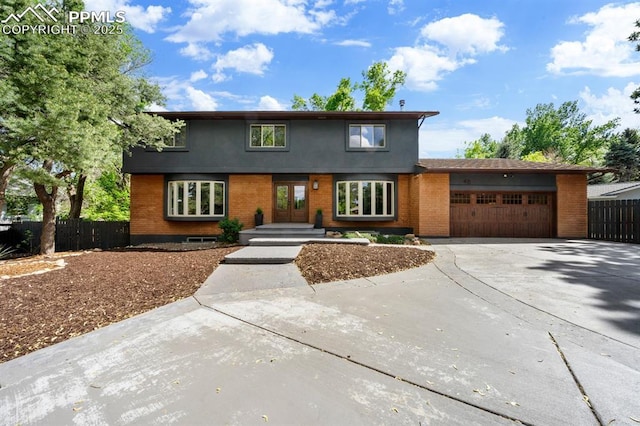 view of front of property with an attached garage, fence, concrete driveway, and brick siding