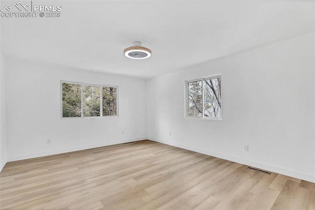 spare room with baseboards, visible vents, and light wood finished floors