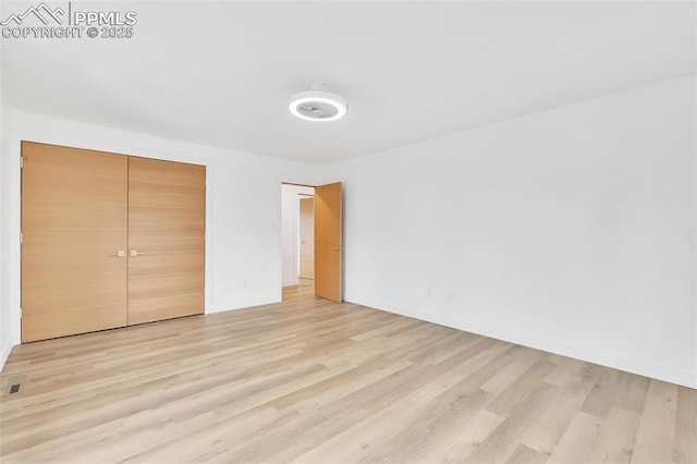 unfurnished bedroom featuring light wood finished floors and a closet