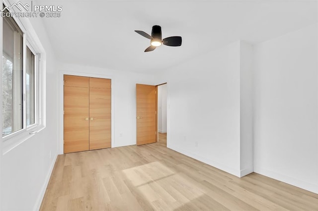 unfurnished bedroom featuring a ceiling fan, a closet, light wood-style flooring, and baseboards