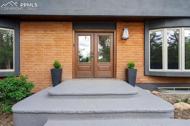 view of exterior entry with brick siding and french doors