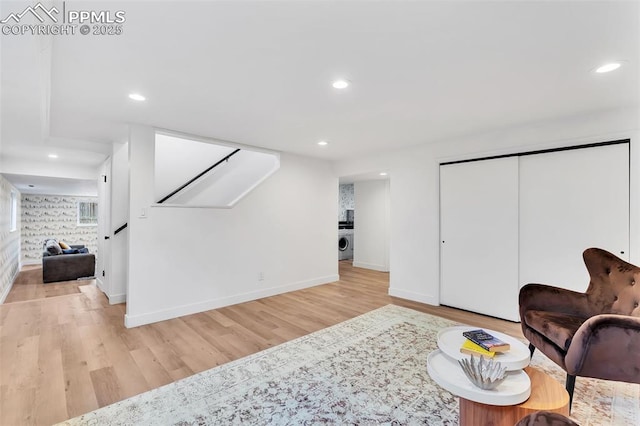 living area featuring light wood-type flooring, washer / dryer, stairway, and recessed lighting