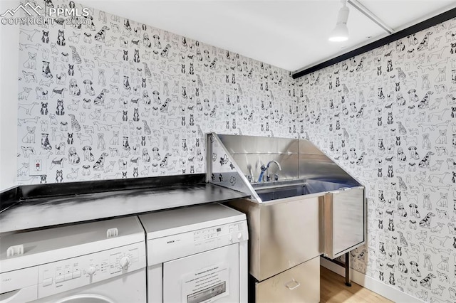 clothes washing area with washer / clothes dryer, a sink, and light wood-style flooring