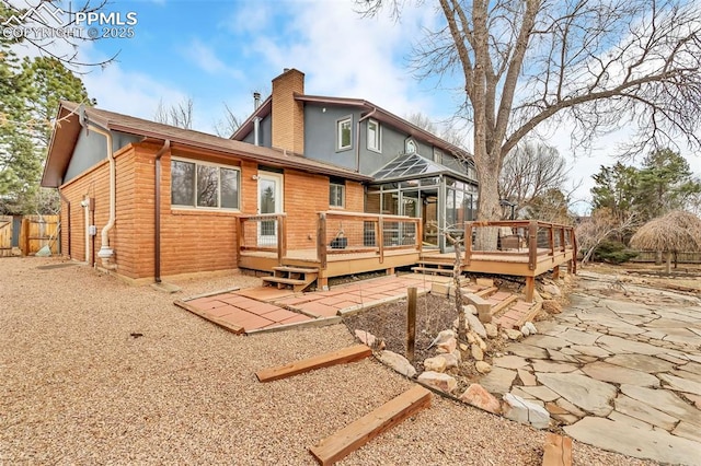 rear view of house featuring a patio area, fence, a chimney, and a wooden deck