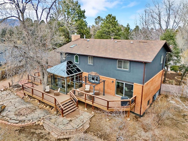 back of property featuring a chimney, fence, a deck, a gazebo, and stucco siding