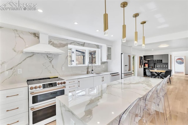 kitchen featuring high quality appliances, hanging light fixtures, light stone countertops, custom exhaust hood, and white cabinetry