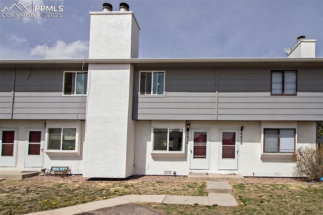 back of property featuring a chimney and stucco siding