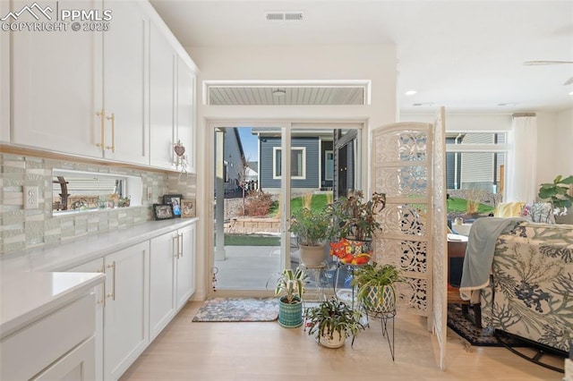 interior space with visible vents, light countertops, white cabinetry, and decorative backsplash