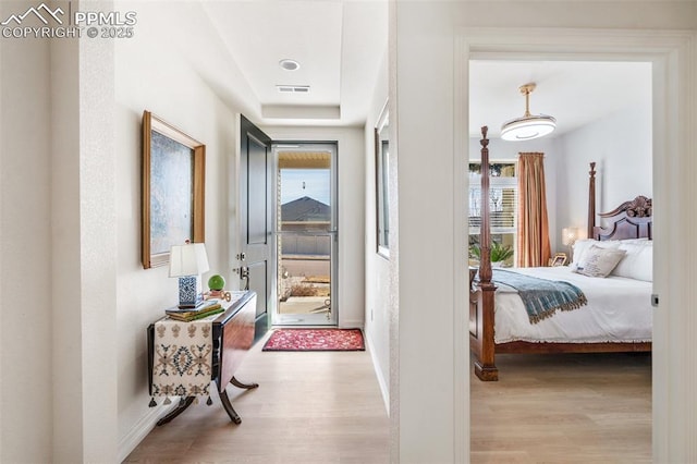 hallway with visible vents, light wood-style flooring, and baseboards