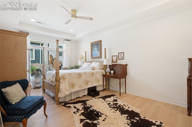 bedroom with light wood-type flooring, baseboards, a tray ceiling, and recessed lighting