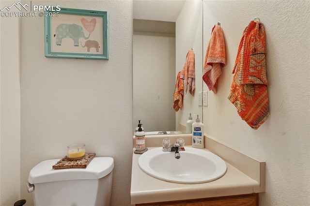 half bathroom with toilet, a textured wall, and vanity