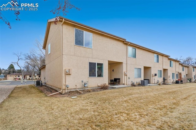 rear view of property with a patio area, a lawn, cooling unit, and stucco siding