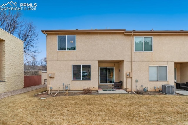 rear view of house with a patio area, a lawn, fence, and stucco siding