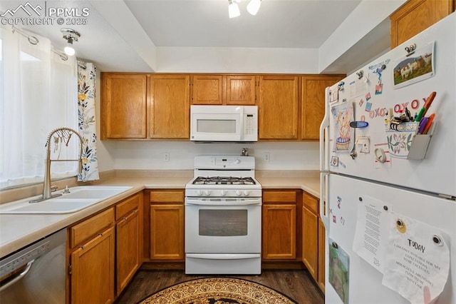 kitchen featuring light countertops, white appliances, a sink, and brown cabinets