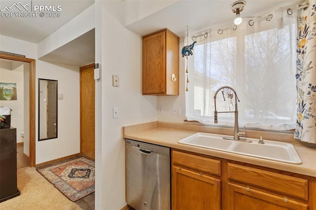 kitchen featuring brown cabinetry, light countertops, dishwasher, and a sink