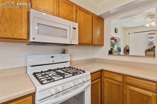 kitchen with white appliances, ceiling fan, light countertops, and brown cabinetry