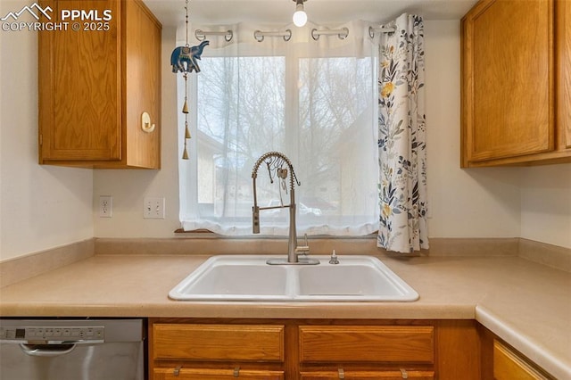 kitchen featuring brown cabinets, light countertops, dishwasher, and a sink