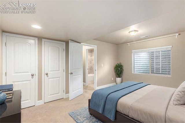 bedroom featuring light carpet, ensuite bath, visible vents, and baseboards