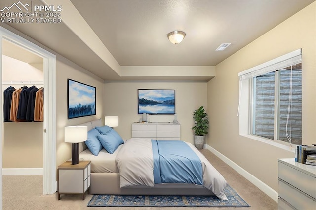 bedroom featuring a closet, visible vents, light colored carpet, a spacious closet, and baseboards