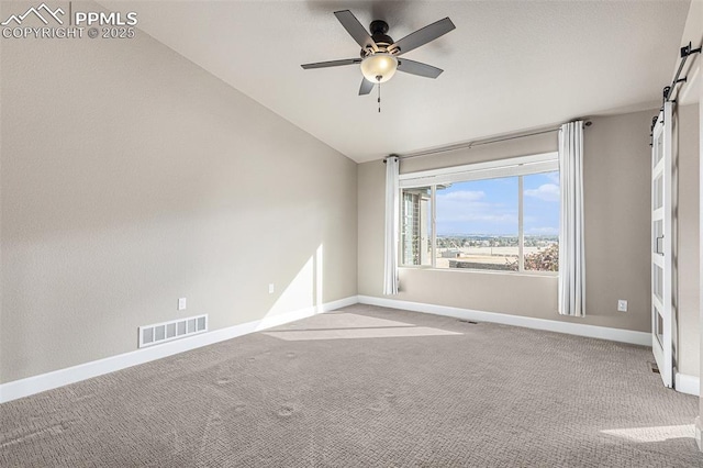 empty room with visible vents, a barn door, a ceiling fan, light carpet, and baseboards