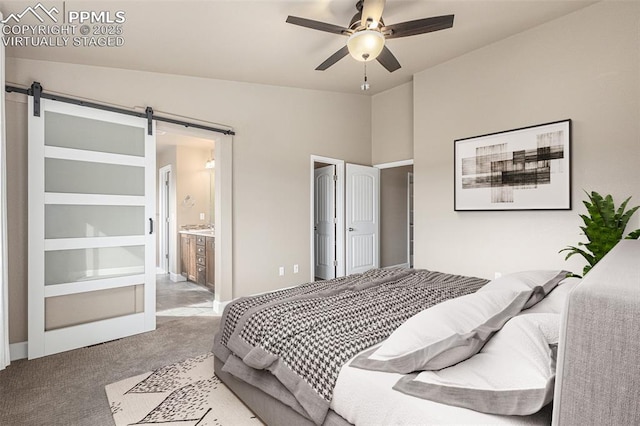 carpeted bedroom featuring a barn door, ceiling fan, and ensuite bathroom