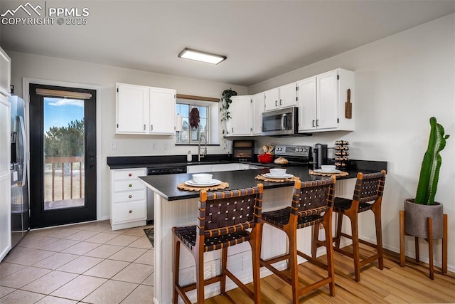 kitchen with dark countertops, stainless steel appliances, a peninsula, and white cabinetry