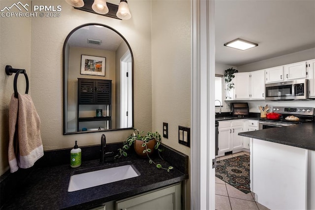 bathroom featuring a textured wall, visible vents, a sink, and tile patterned floors