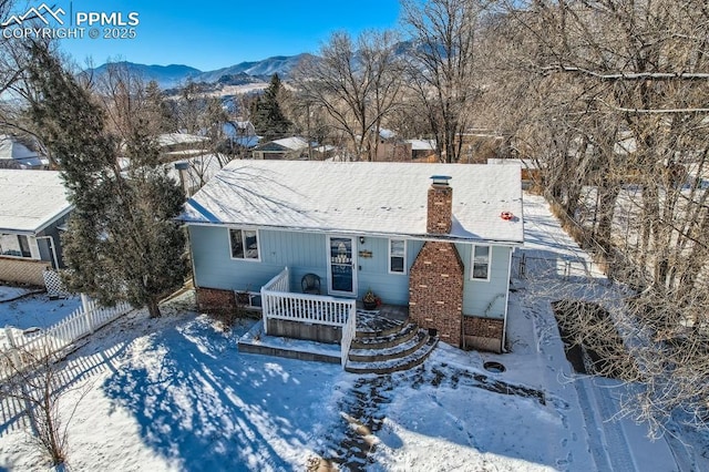 single story home featuring a mountain view, a chimney, and fence