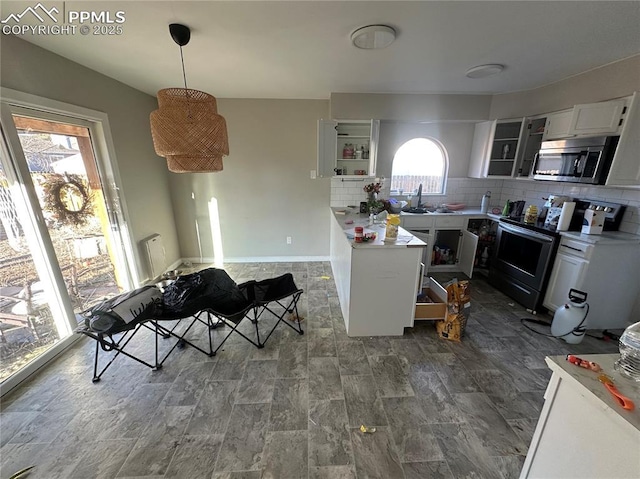 kitchen featuring appliances with stainless steel finishes, white cabinets, light countertops, and decorative light fixtures