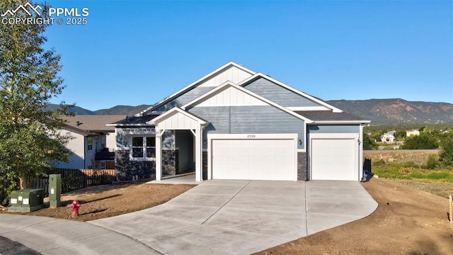 view of front of house with concrete driveway, an attached garage, board and batten siding, a mountain view, and fence