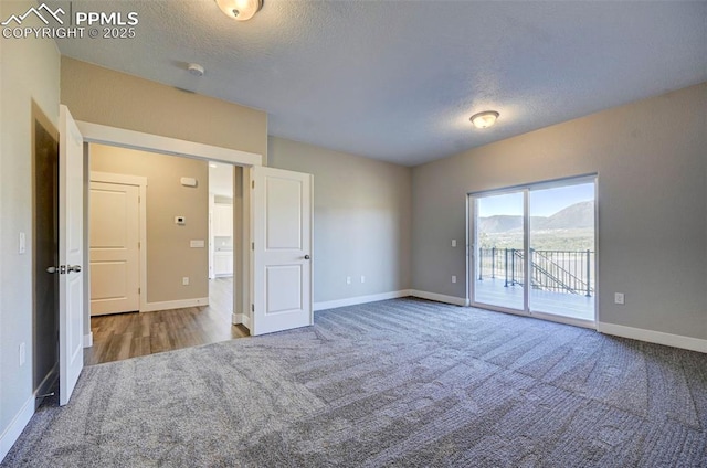 unfurnished bedroom featuring access to exterior, carpet, a mountain view, and baseboards