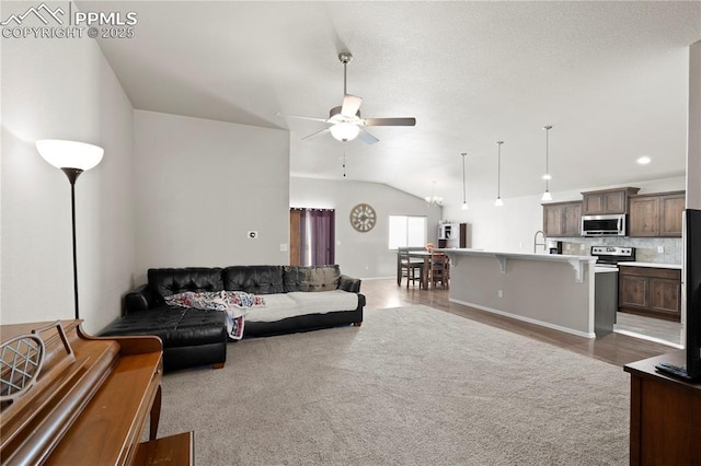 living area featuring lofted ceiling, a ceiling fan, and light wood-style floors