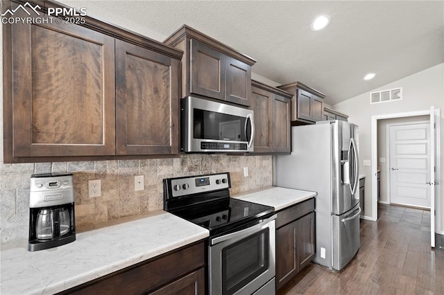 kitchen featuring stainless steel appliances, dark brown cabinets, light countertops, and visible vents