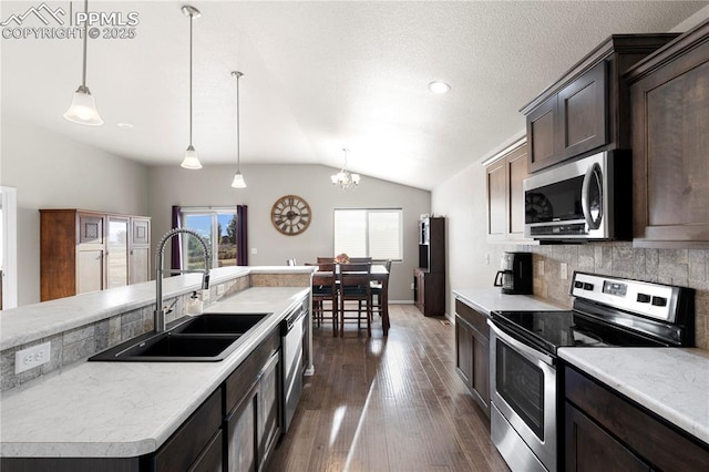 kitchen featuring a center island, decorative light fixtures, appliances with stainless steel finishes, vaulted ceiling, and a sink