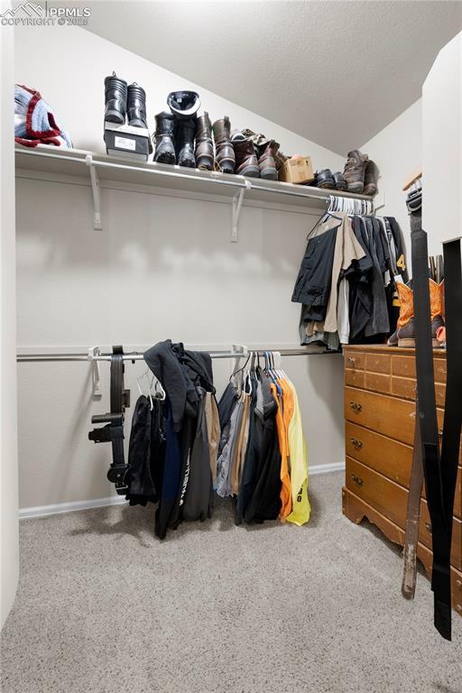 walk in closet with lofted ceiling and light colored carpet