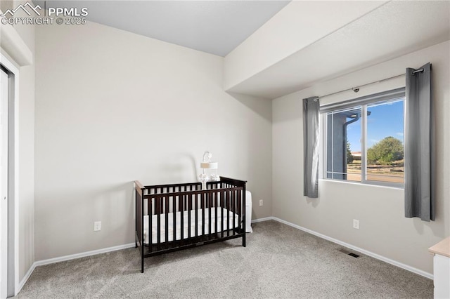 carpeted bedroom with a nursery area, visible vents, and baseboards