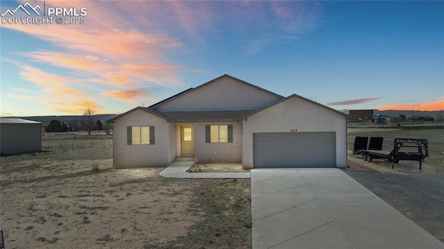 single story home featuring driveway, an attached garage, and stucco siding