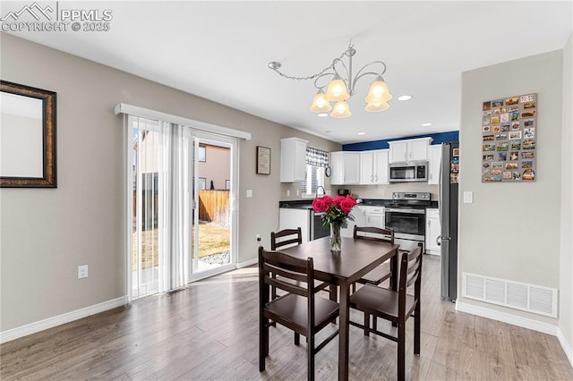 dining space with a healthy amount of sunlight, an inviting chandelier, visible vents, and light wood finished floors