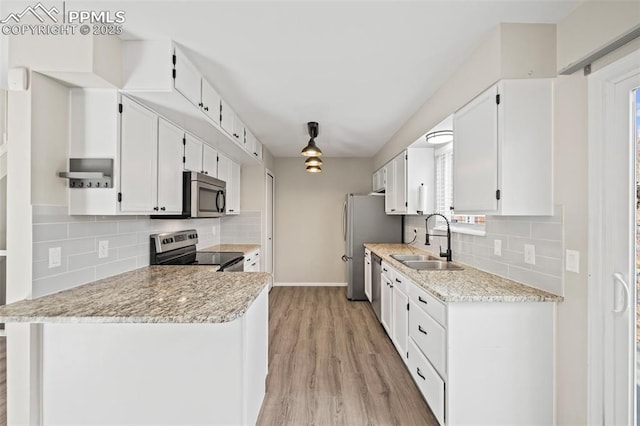 kitchen with decorative backsplash, light wood-style flooring, stainless steel appliances, white cabinetry, and a sink